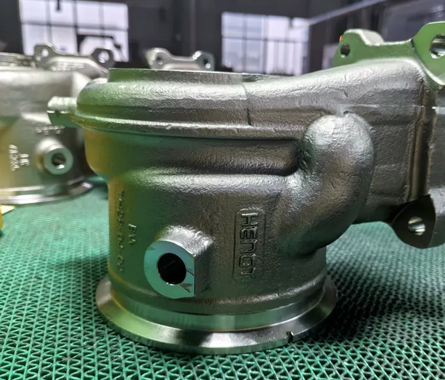 Machined cast metal housing with finished bores and mounting ears for industrial and automotive applications
