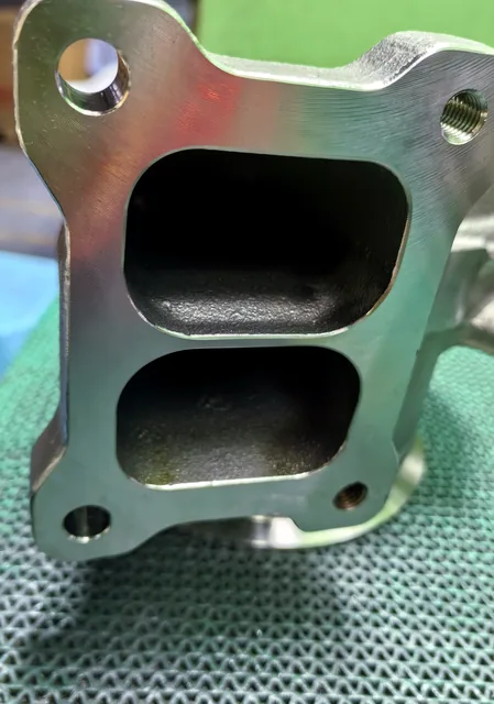 Machined flange, threaded holes and port openings on a precision casting component